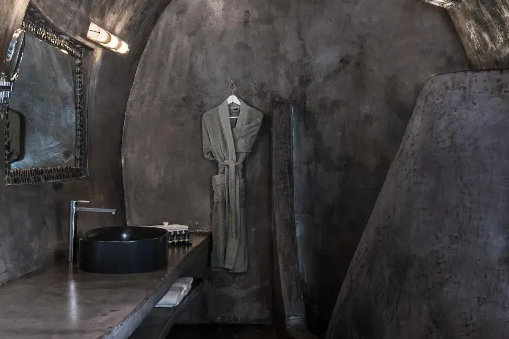 Edles Badezimmer mit dunklen Wänden, einem Bademantel und stilvollen Waschbecken.