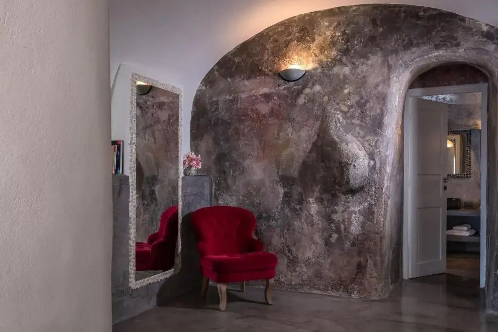 Ecke mit rotem Sessel und Spiegel an einer stilvoll gestalteten Steinwand