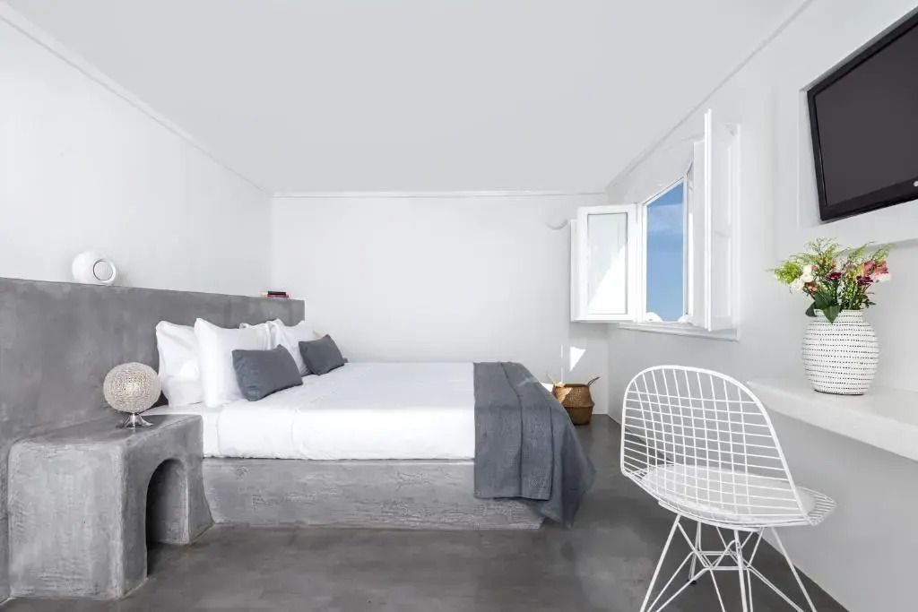 Helles Zimmer mit Doppelbett und grauen Akzenten. Fenster mit Meerblick.