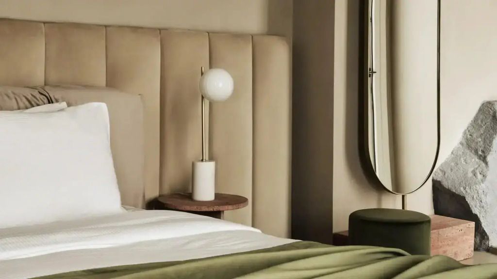 Nahaufnahme eines Bettes mit stilvoller Lampe und gepolstertem Kopfteil