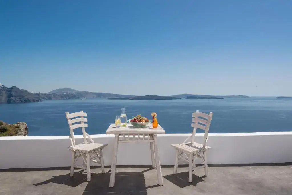 Balkon mit Tisch und Stühlen vor malerischer Meereslandschaft