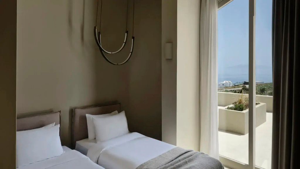 Elegantes Schlafzimmer mit zwei Einzelbetten und Blick auf Natur.