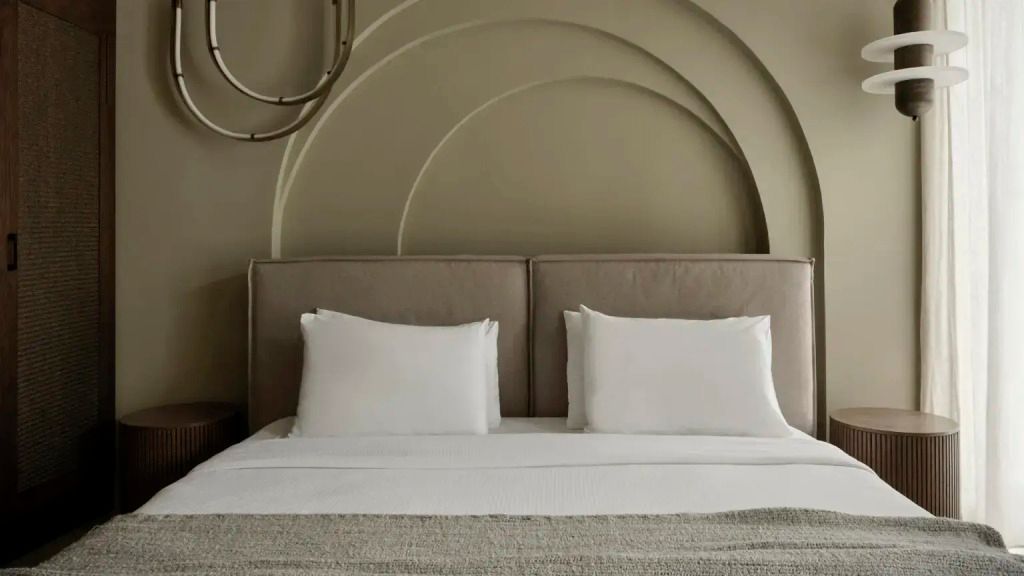 Stilvolles Bett mit dekorativem Wanddesign im Andronis Concept Hotel