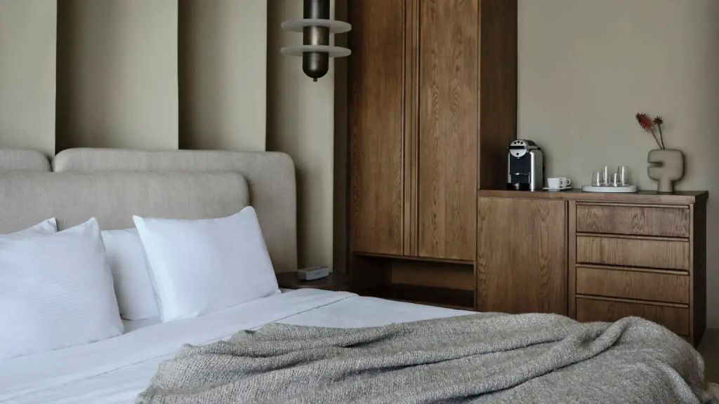 Holzschrank und luxuriöses Bett in schickem Hotelzimmer mit stilvoller Wandgestaltung