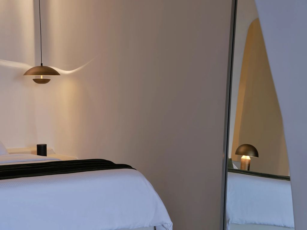 Teilansicht eines Bettes mit dezenter Beleuchtung und Spiegel. Minimalistische Eleganz