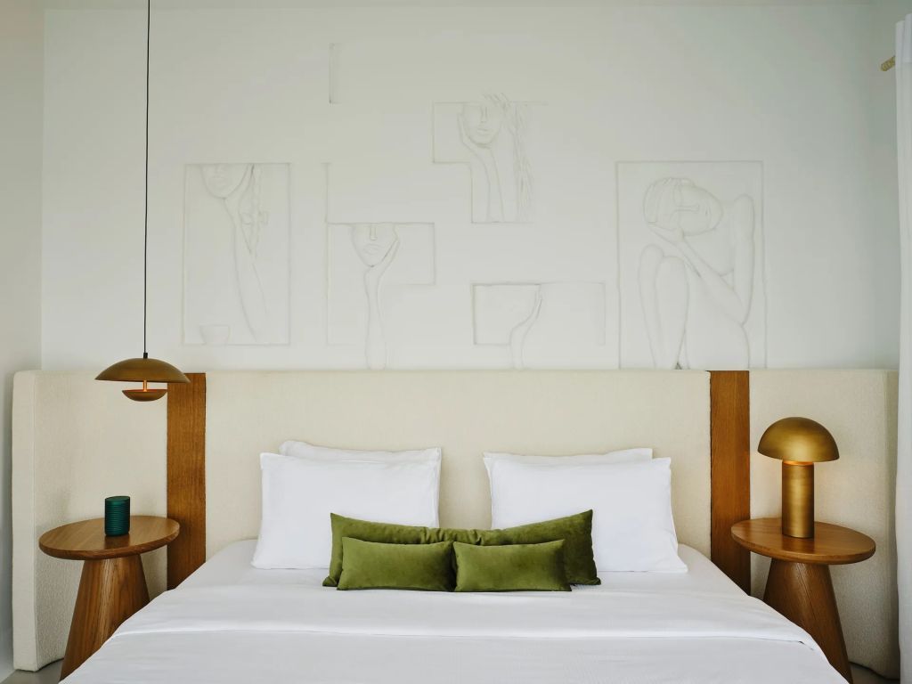 Bett mit grünen Kissen und stilvollen Nachttischen in der Suite