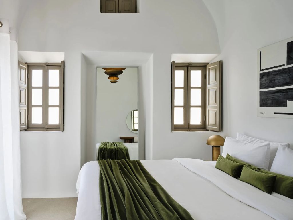 Elegantes Schlafzimmer mit weißer Bettwäsche und grünem Wurf über dem Bett.
