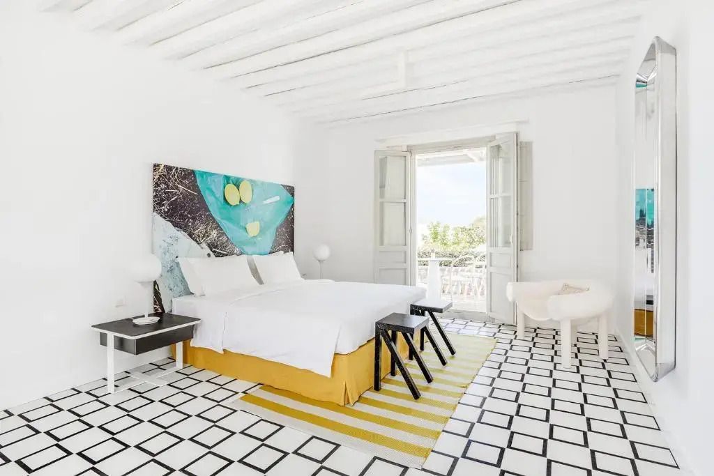 Helles Deluxe Doppelzimmer mit modernem Dekor und Doppelbett, das auf einen Balkon öffnet.