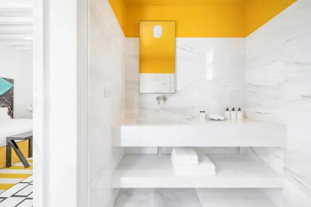 Modernes Badezimmer mit gelben Akzenten und weißem Marmordesign.