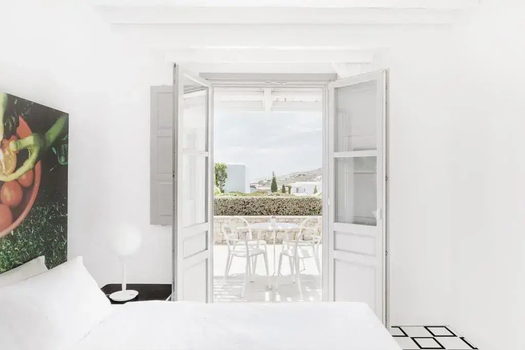 Blick von einem hellen Zimmer auf eine private Terrasse mit Sitzgelegenheiten