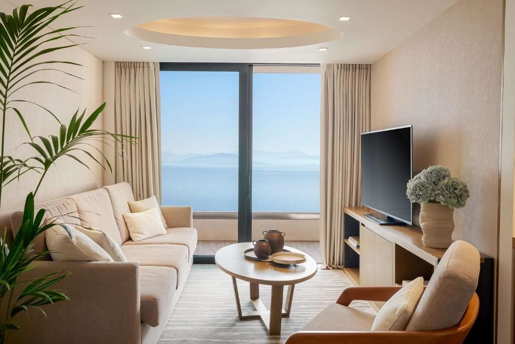 Wohnbereich mit Sofa, Couchtisch und TV vor Meerblickfenster