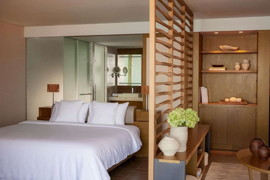 Doppelbett mit Holzelementen und großer Fensterfront im Angsana Corfu Resort