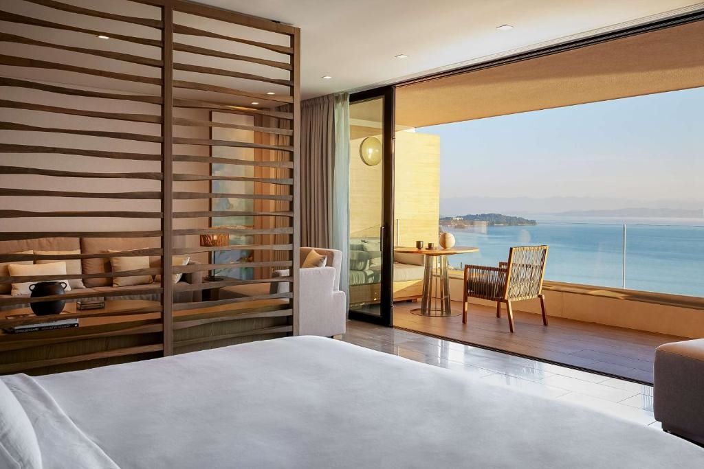 Bett mit Meerblick-Balkon und Sitzgelegenheit im Angsana Corfu Resort