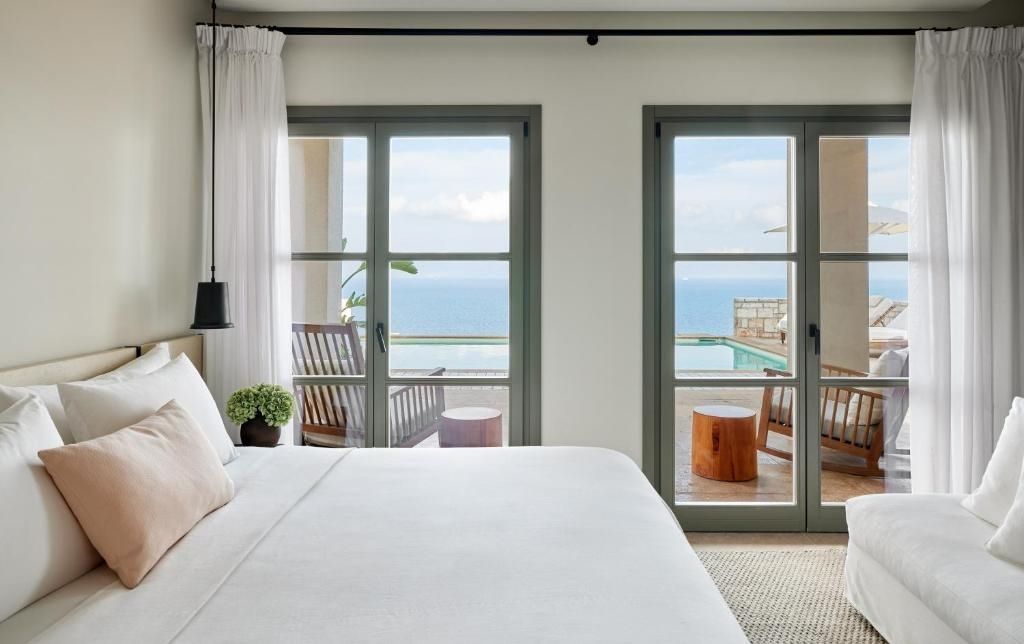 Schlafzimmer mit zwei Fenstern zur Terrasse und Blick auf das Ionische Meer sowie Pool