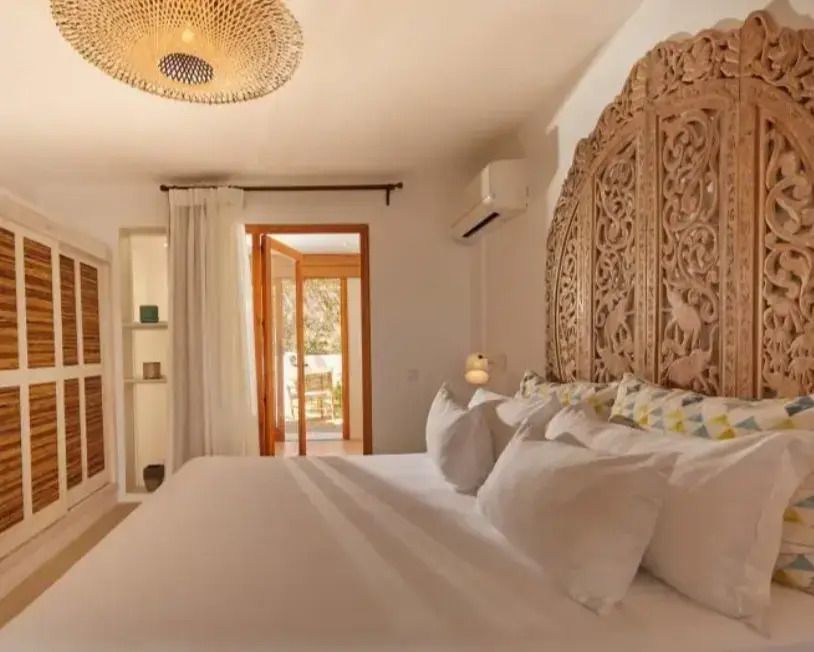 Fein dekoriertes Schlafzimmer mit handgeschnitztem Kopfteil und Balkonzugang.