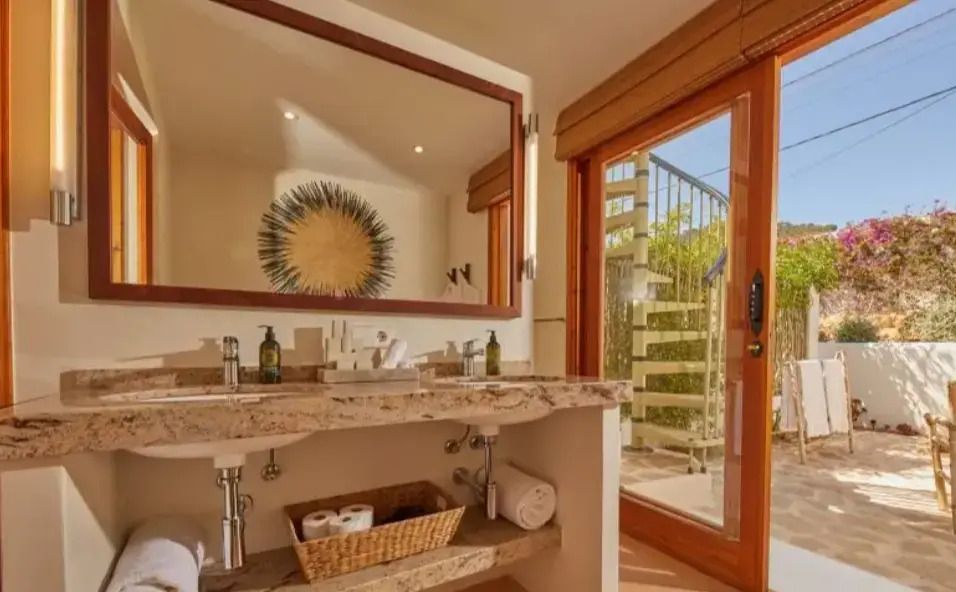 Modernes Badezimmer mit großem Spiegel und Zugang zur Terrasse.