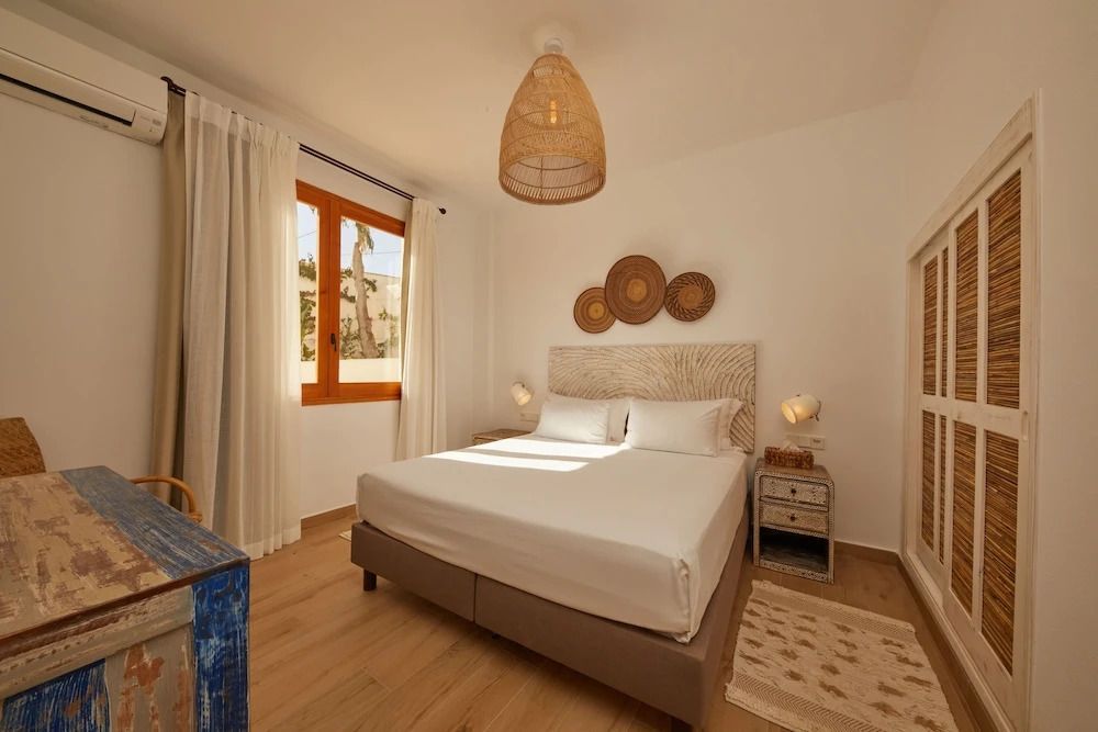 Helles Schlafzimmer mit Doppelbett, stilvoller Dekoration und großem Fenster