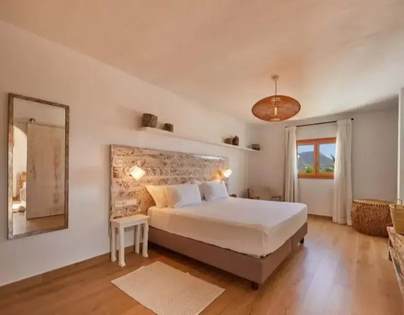 Helles Schlafzimmer mit Doppelbett und Steinwand in der Petunia Suite mit Meerblick.