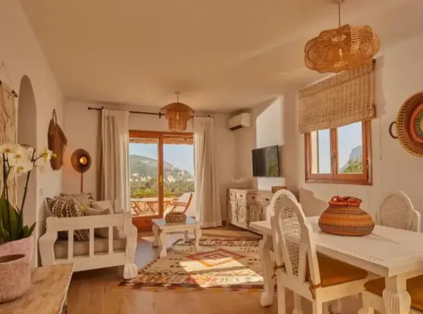 Wohnzimmer mit großen Fenstern und Zugang zum Balkon mit Blick auf die Landschaft.