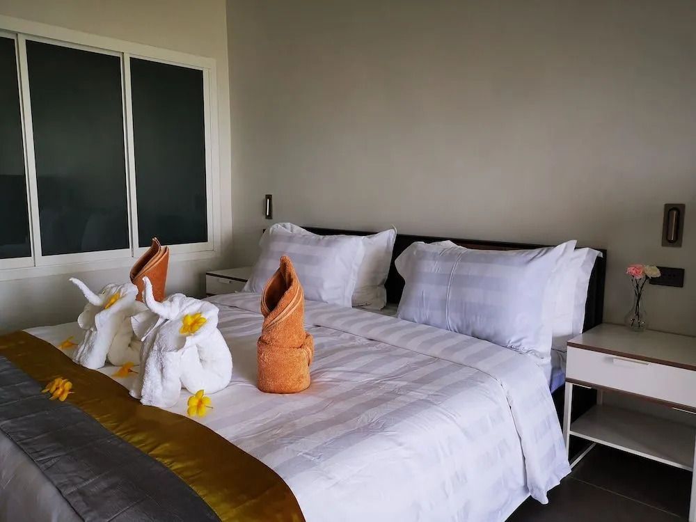 Hotelbett mit eleganter Wäsche und dekorativen Handtuchfaltungen