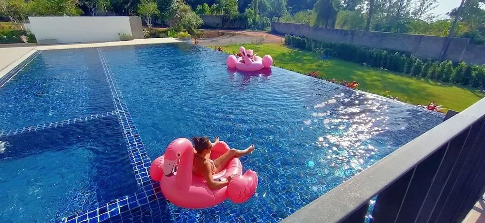 Infinity Pool mit zwei aufblasbaren rosa Flamingos und üppiger Vegetation