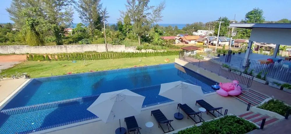 Infinity Pool mit Liegestühlen und Blick ins Grüne und auf das Meer