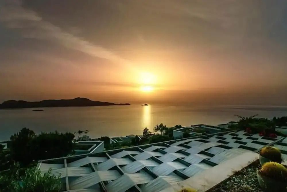 Beeindruckender Sonnenuntergang über dem Meer mit Hotelarchitektur im Vordergrund