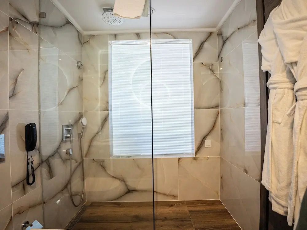 Moderne Duschkabine mit Marmorfliesen und Glastür im Badezimmer