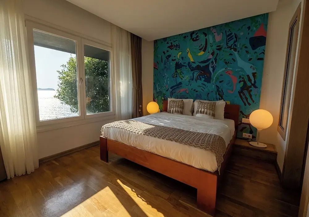 Komfortzimmer mit Doppelbett und Blick auf das Meer durch große Fenster