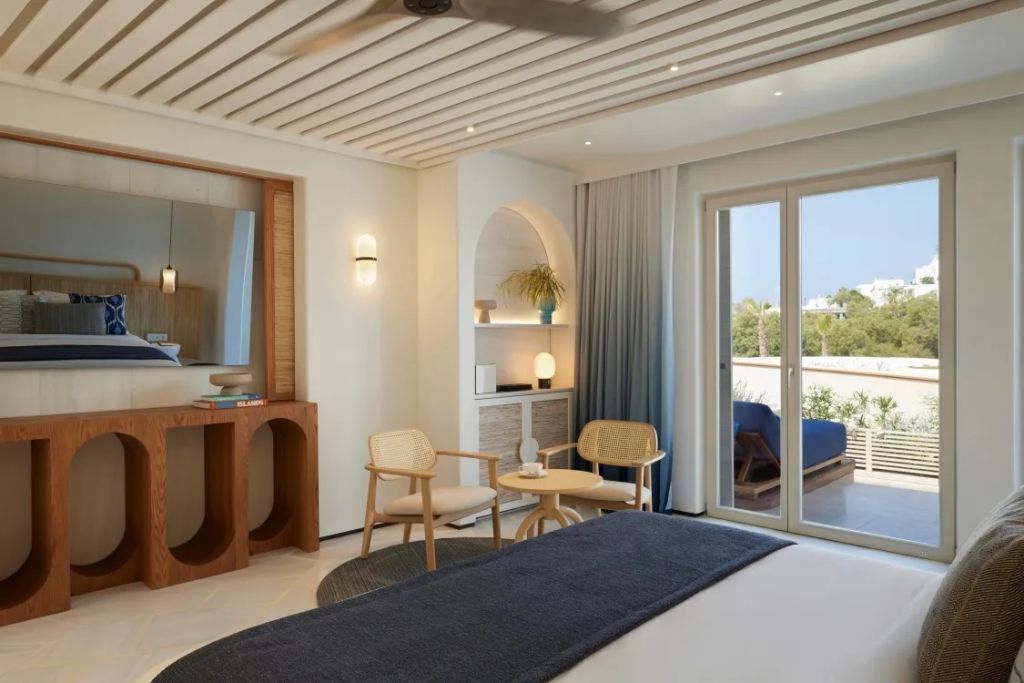 Helles Zimmer mit Doppelbett, Sitzbereich und Zugang zur Terrasse