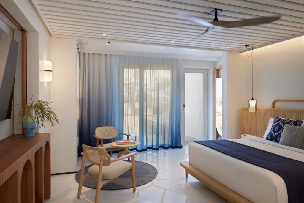 Doppelzimmer mit großem Bett, modernen Möbeln und blauem Vorhang