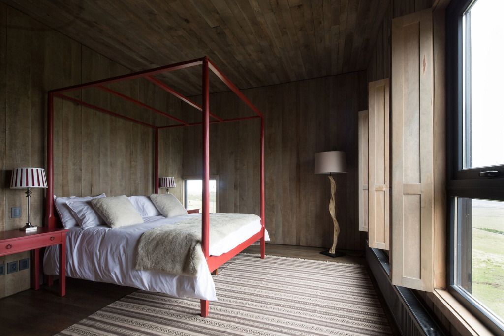 Schlafzimmer mit rotem Himmelbett und Fenstern mit Holzläden
