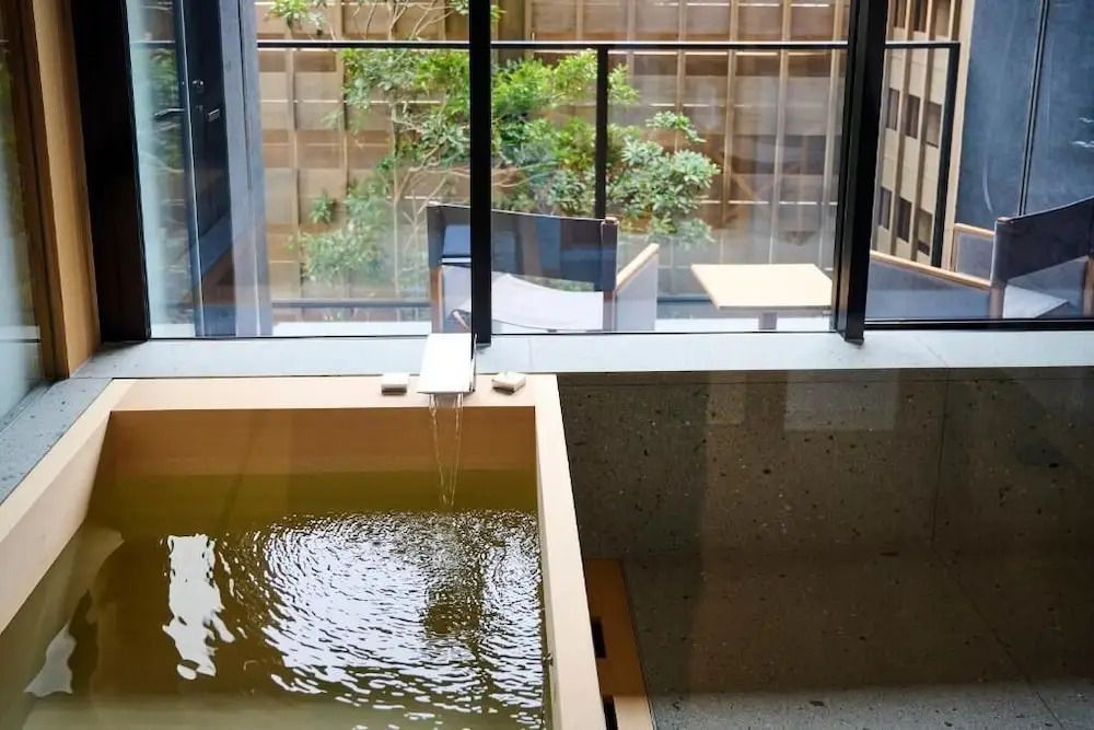 Japanisches Badezimmer mit Blick auf Innenhof und Holzbadewanne