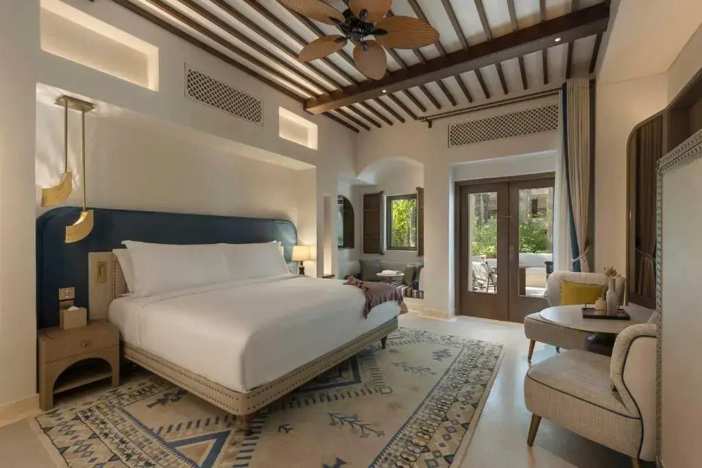Geräumiges Schlafzimmer mit Doppelbett und Zugang zur Terrasse im Hotel Bab Al Shams
