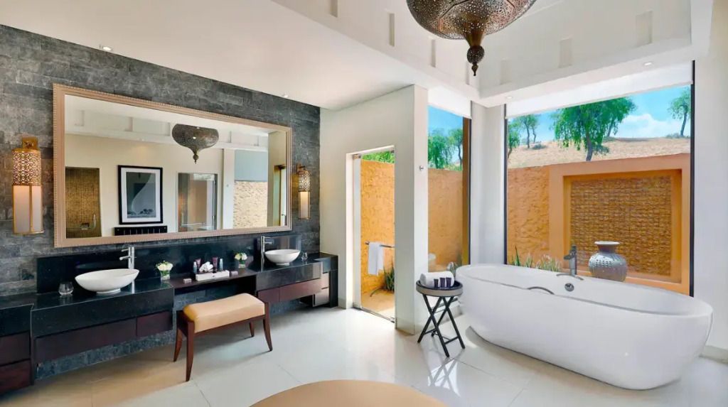 Luxuriöses Badezimmer mit freistehender Badewanne und Blick in den begrünten Außenbereich
