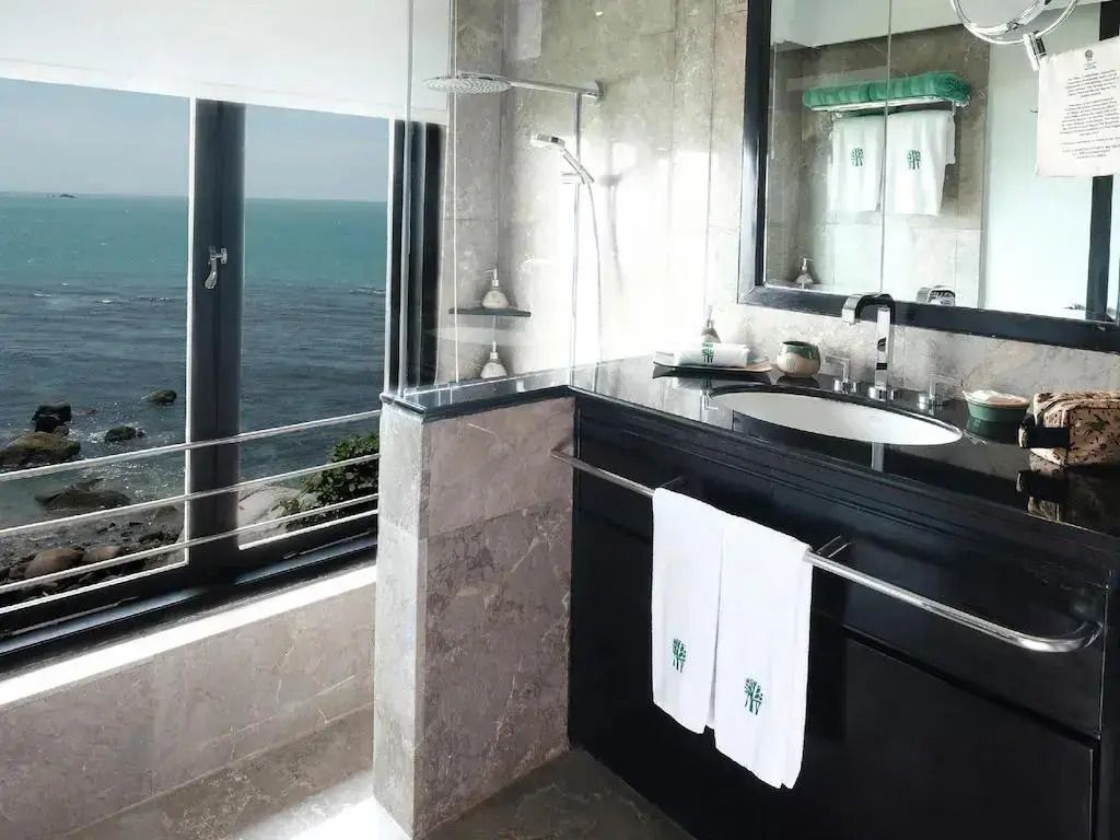 Modernes Badezimmer mit Blick auf das Meer durch große Fenster