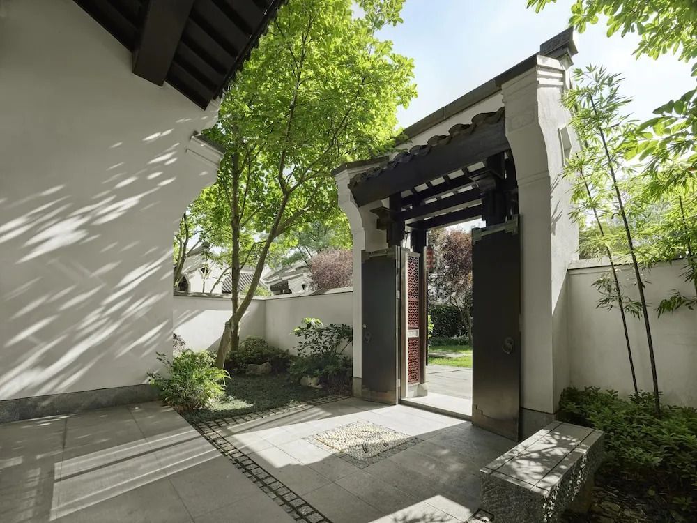 Eingangstor einer Villa umgeben von elegantem, grünem Garten im asiatischen Stil.