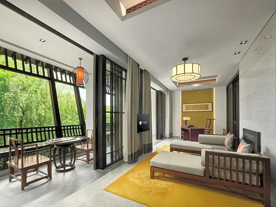 Helle Suite mit elegantem Wohnbereich und Balkon mit Blick auf die Natur.
