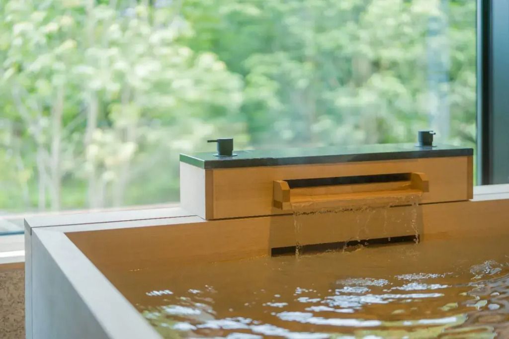 Holzbadewanne mit fließendem Wasser und Waldblick