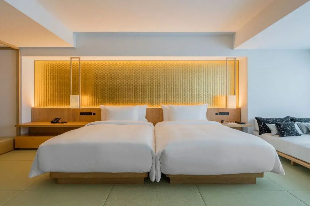 Zwei Einzelbetten mit goldener Akzentbeleuchtung in einem Hotelzimmer.