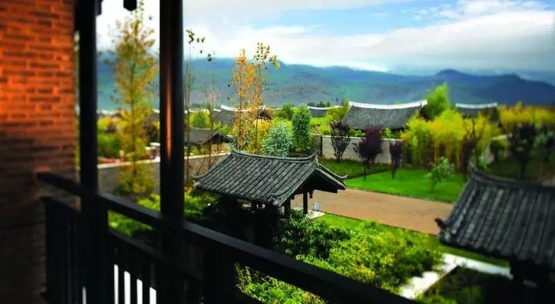 Blick von der Veranda auf üppigen Garten mit traditioneller Architektur und Bergpanorama