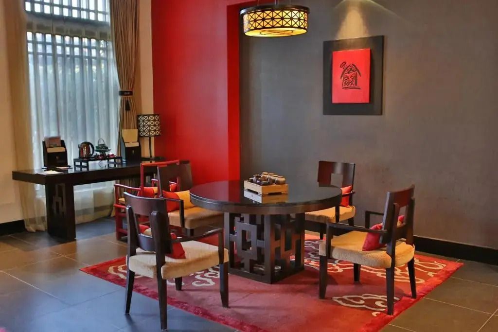 Einladender Wohnbereich mit runden Holzmöbeln und rotem Akzent im Banyan Tree Lijiang