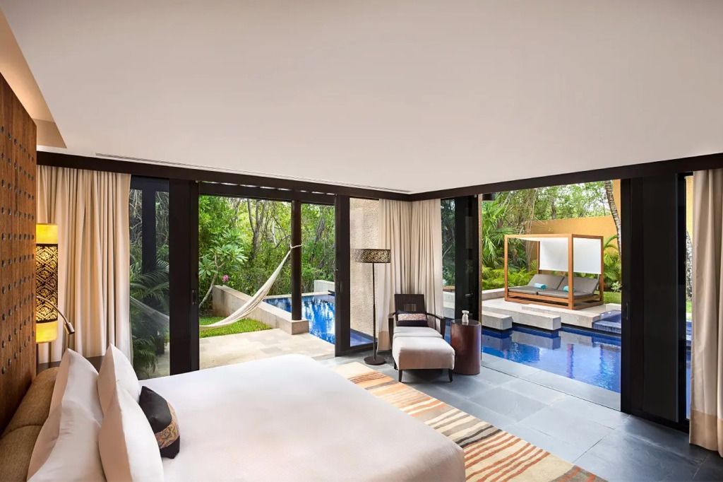 Helle Schlafzimmeransicht mit Blick auf privaten Pool und Hängematte im tropischen Garten