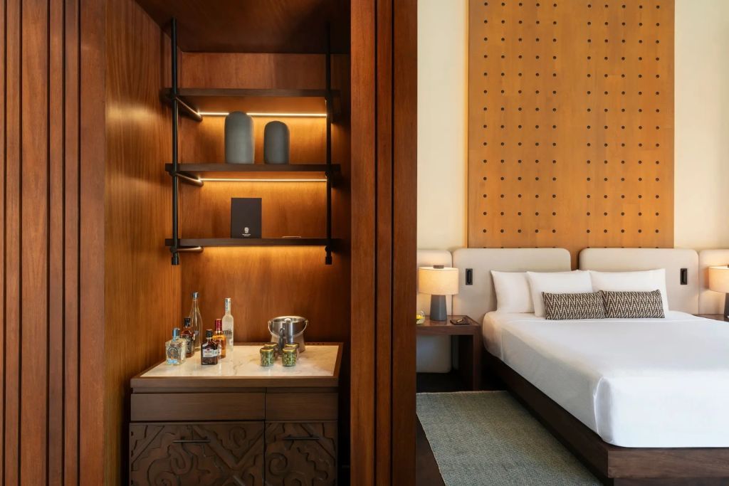 Komfortabler Wohnbereich mit Minibar und hellem Schlafzimmer