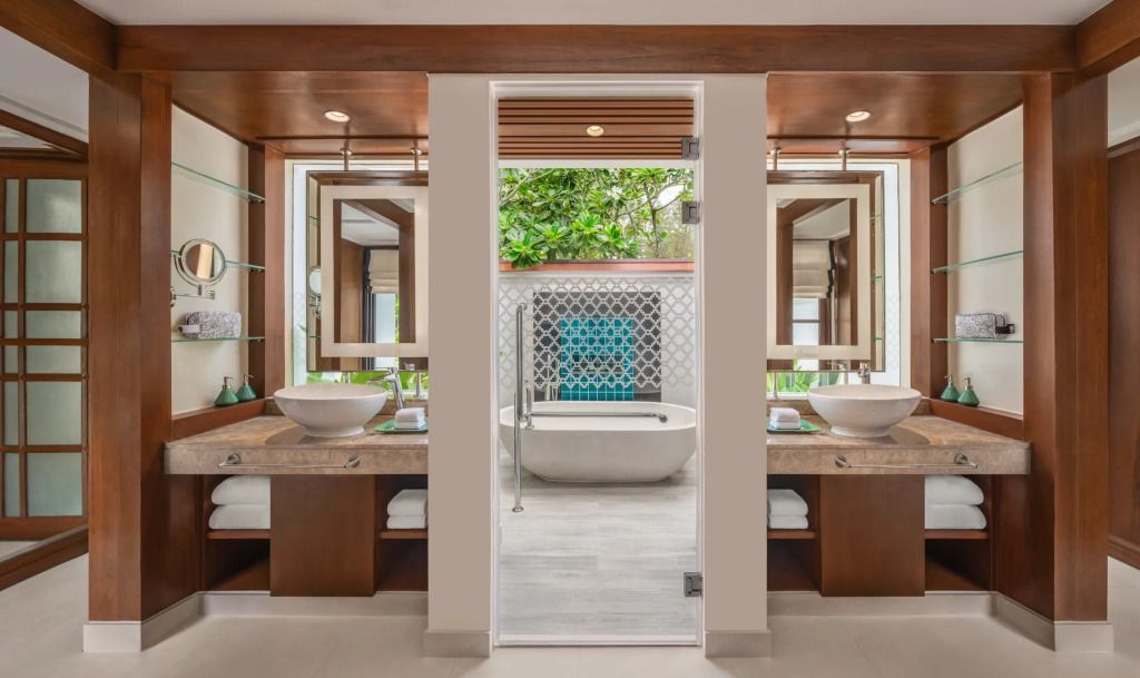 Modernes Badezimmer mit zwei Waschbecken und freistehender Badewanne vor grüner Aussicht