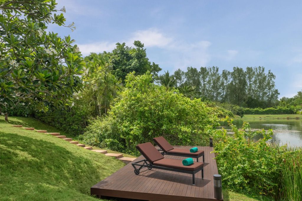 Grüne Gartenlandschaft mit Holzterrasse und Liegestühlen im Freien