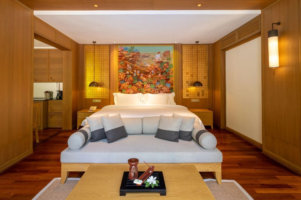 Luxuriöses Schlafzimmer mit Doppelbett und Sofa in warmer Holzausstattung.