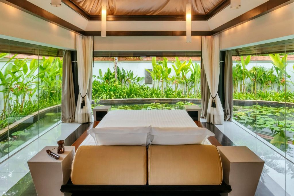 Luxuriöse Villa mit Blick auf grünen Garten und Pool vom Doppelbett aus
