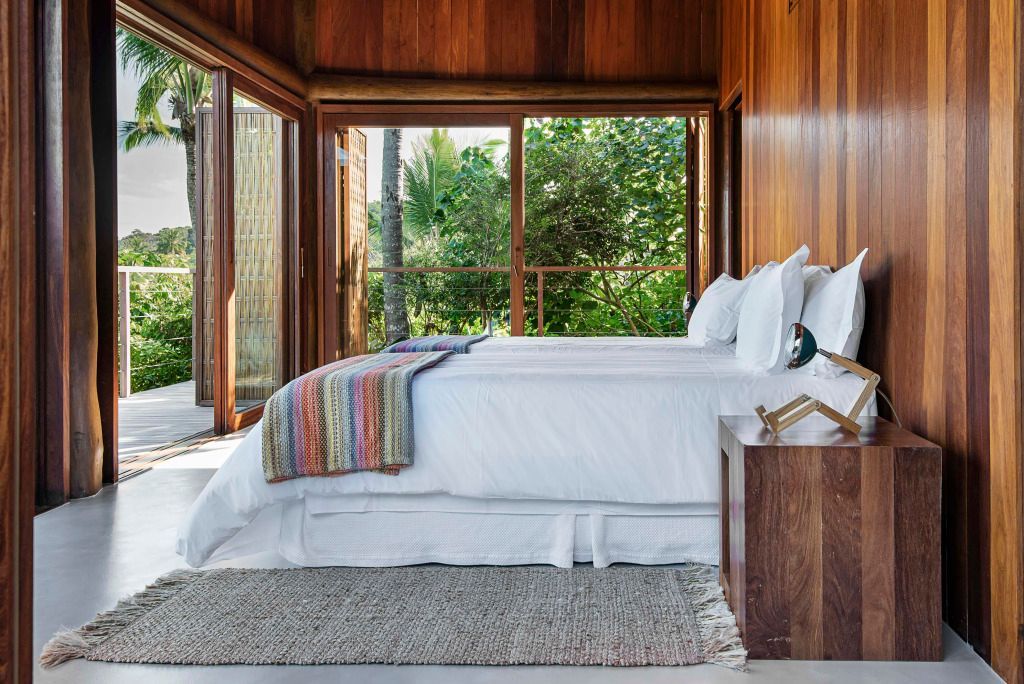 Modernes Schlafzimmer mit zwei Betten und Aussicht auf tropische Vegetation.