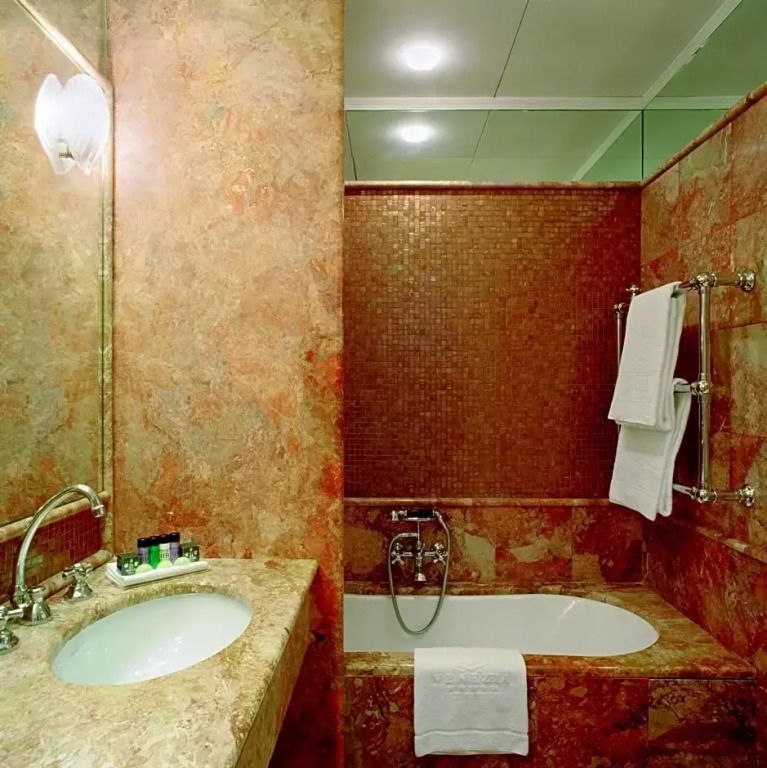 Luxuriöses Badezimmer mit Marmorverkleidung und Badewanne im Bauer Palazzo Hotel